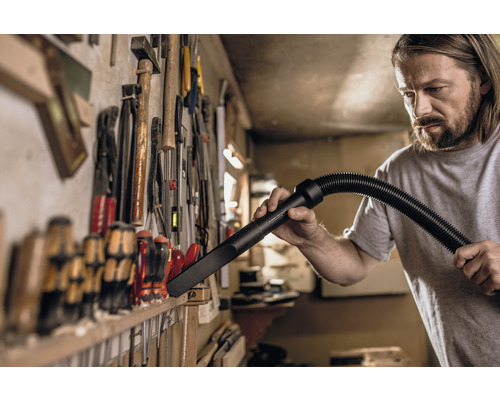 Ambachtsman reinigt werkbank met stofzuiger mondstuk voor gereedschapswand