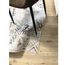 Decoratief tapijt met geometrische patronen onder een stoel op een houten vloer.