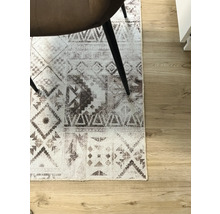 Tapijt met grafisch patroon onder een stoel op een houten vloer.