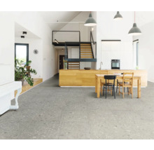 Lichte woonkamer met grijze vloertegels, keukentafel en trap