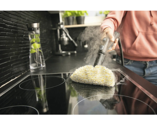 Stoomreiniger in gebruik op een kookplaat in een keuken.