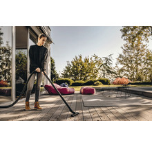 Een vrouw maakt een houten terras schoon met een stofzuiger voor buiten.