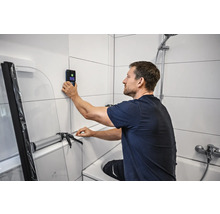 Man gebruikt wandscanner in de badkamer voor badkamerrenovatie.