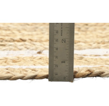 Close-up van een jute vloerkleed met een meetlint om de dikte te meten