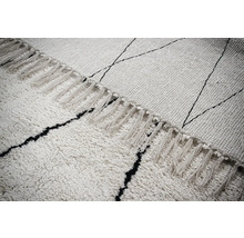 Detailopname van een vloerkleed met franjes en een grafisch patroon