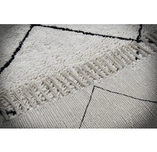 Detailweergave van een tapijt met geometrisch patroon en franjes