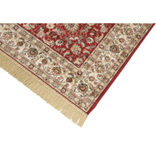 Detail van een rood tapijt met bloemmotief en franjes