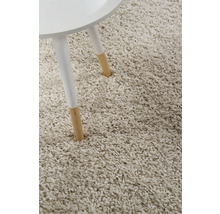 Detailopname van een beige hoogpolig tapijt naast een tafelpot.