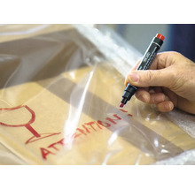 Hand beschrijft pakket met een stift en de waarschuwing breekbaar