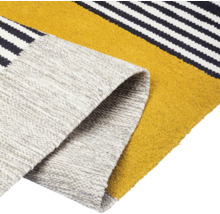 Detailweergave van een vloerkleed met streepmotief en opgerolde rand