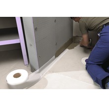 Een vakman voegt een douchewand af met afdichtband.