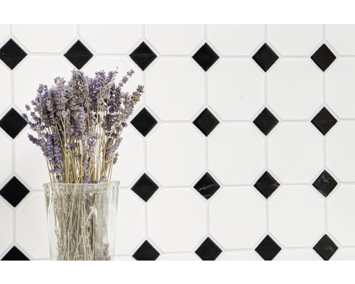 Decoratieve tegelwand met geometrisch patroon en een bos lavendel in een glas.