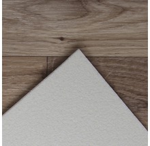 Detailopname van een witte vinyltegel op een houten vloer.