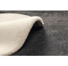 Detailopname van een rond, lichtgekleurd vloerkleed met hoogpolig oppervlak