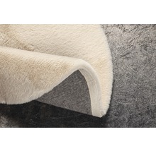 Detailopname van een beige hoogpolig tapijt met een textielen rug