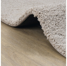 Detailopname van een beige badmat op een houten vloer