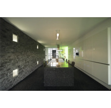Lichte ruimte met stenen decoratieve wand, eettafel en kitchenette.