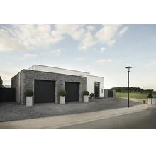 Buitenkant van een modern huis met garage, stenen gevel en verharde oprit