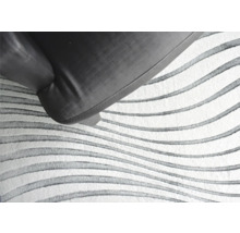 Detail van een vloerkleed met golvend patroon en fauteuil