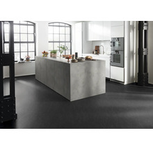 Lichte keuken met kookeiland, witte kasten en zwarte vloer.