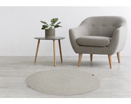 Woonkameropstelling met rond vloerkleed, fauteuil en bijzettafel met plant