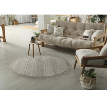 Woonkamer met rond vloerkleed, bank en fauteuil van hout