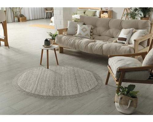 Woonkamer met rond vloerkleed, bank en fauteuil van hout