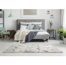 Lichte slaapkamer met bed, tapijt en decoraties voor een vriendelijke sfeer.