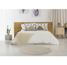 Slaapkamer met houten bed, kussens met patronen, sprei en rond tapijt