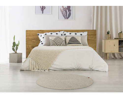 Slaapkamer met houten bed, kussens met patronen, sprei en rond tapijt