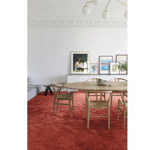 Een eetkamer met een ovale houten tafel, stoelen en een rood tapijt.