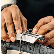 Close-up van een persoon die een fietsband met een bandenlichter monteert.