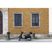 Gebouw met bakstenen gevel, ramen met metalen tralies en een scooter