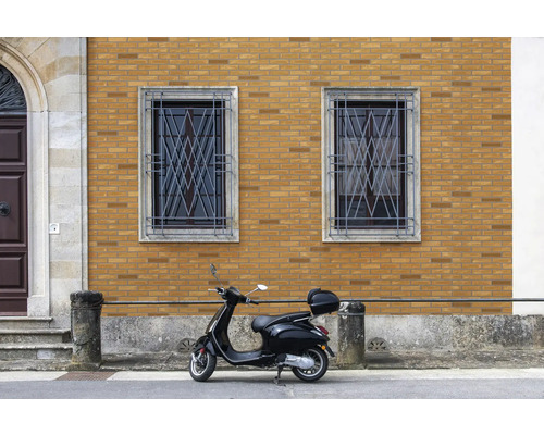 Gebouw met bakstenen gevel, ramen met metalen tralies en een scooter