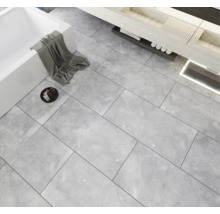 Badkamer met ligbad, wastafel en vloertegels met marmerlook