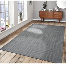 Grijs vloerkleed met geometrisch patroon in een lichte kamer op een houten vloer