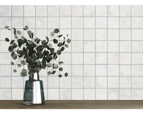 Wand met vierkante tegels en een vaas met eucalyptus op een houten tafel