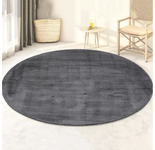 Grijs, rond vloerkleed in kamer met rotan stoel en tafel