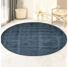 Blauw rond vloerkleed in een lichte kamer met mand en tafel
