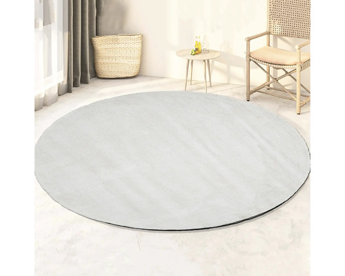Rond vloerkleed in lichte kamer met mand, bijzettafel en stoel