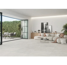 Lichte woonkamer met tegelvloer, terrasdeur en tuinmeubelen