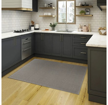 Grijs tapijt in een moderne keuken met grijze kasten en houten vloer.