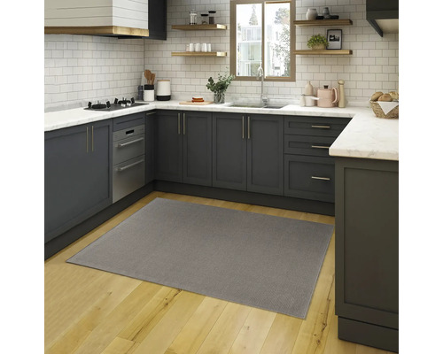 Grijs tapijt in een moderne keuken met grijze kasten en houten vloer.