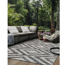 Scene van een terras met een grijze rotan bank, een grijze hangstoel en een buitentapijt met zigzagpatroon.