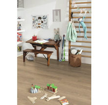 Kinderkamer met houten bureau, bank, speelgoed en lichte laminaatvloer.