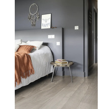 Slaapkamer met bed, nachtkastje en een lichte houten vloer.