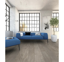 Woonkamer met blauwe bank, hocker en lichte houten vloer