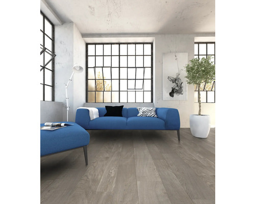 Woonkamer met blauwe bank, hocker en lichte houten vloer