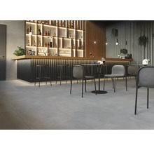 Interieur met bar, barkrukken, tafels en stoelen op een tegelvloer.