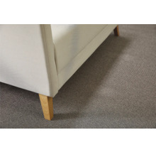Detail van een witte bank met houten poten op een grijs tapijt